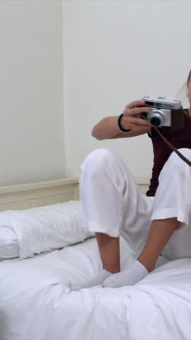Young sisters taking pictures and having fun in their bedroom with a vintage film camera, capturing precious moments of their childhood friendship and sisterhood with joyful smiles