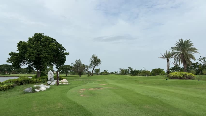 Golf course fairway with large trees and tropical landscape in Thailand