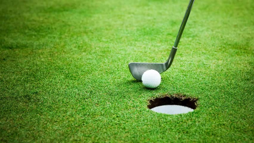 A person is standing on a golf course and preparing to hit a golf ball with a golf club wrong goal.