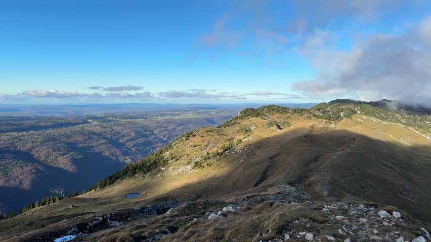 Panoramic view of Jura Mountains landscape on sunny day. Slow pan left