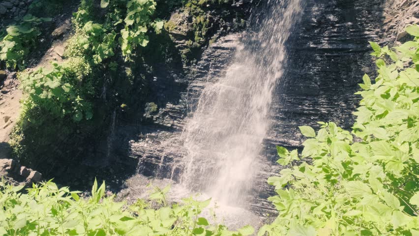 Scenic mountain waterfall streaming down rocky cliff in wild forest