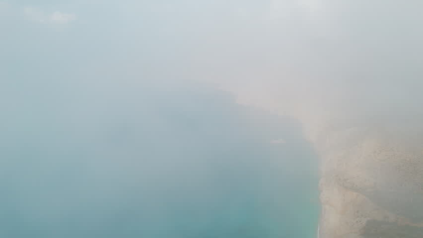 Aerial view of foggy coastline with blue sea and rocky cliffs in Kefalonia Greece