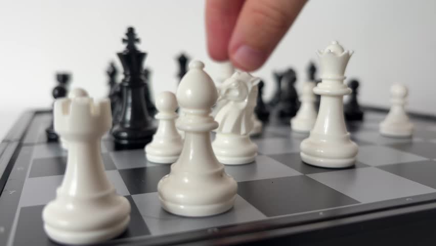 Person Playing Chess and Moving Piece on Board