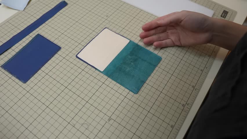Craftsperson aligns two tone leather card cover halves together