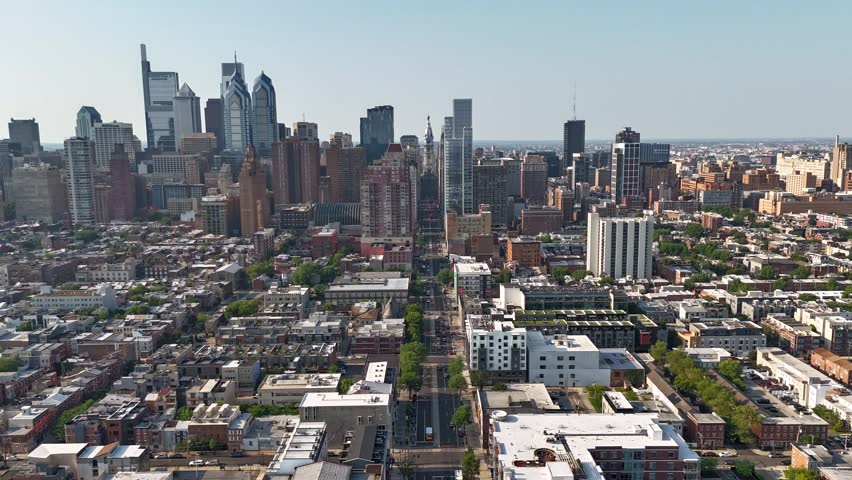 An aerial timelapse of a sprawling city skyline dominated by numerous skyscrapers around Broad Street under a clear sky in Philadelphia, Pennsylvania