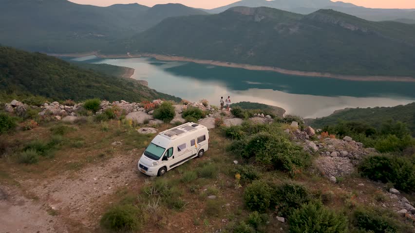 Montenegro stunning landscape of Bilecko jezero. Enjoy incredible views from the heights, showcasing a serene lake surrounded by majestic mountains. A couple camp in a camper van