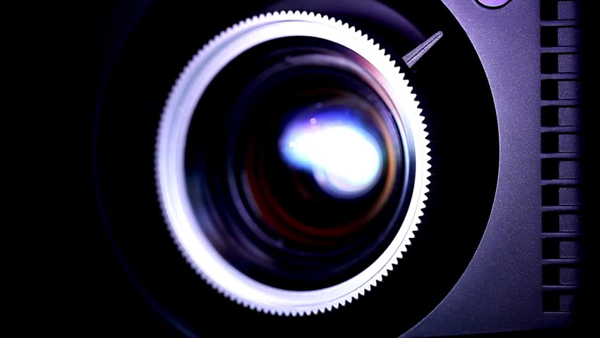 Detailed shot of a professional camera lens highlighting its optical elements and metallic textures, capturing light in a striking manner.