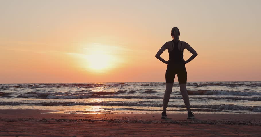 Woman stretching on the beach at sunset. Outdoor fitness and wellness