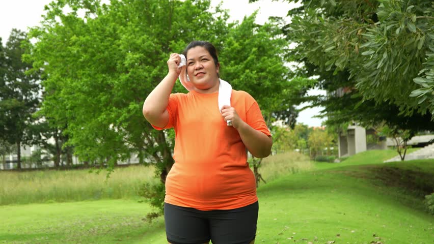 Resting after workout: A determined individual, adorned in sporty attire and clutching a towel around their neck, finds a moment of respite after an exercise session, set amidst a vibrant park.