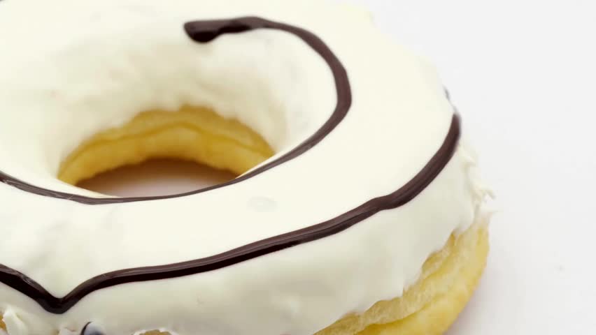 Donut with white frosting and chocolate swirl topping rotates slowly on a white background. Perfect for food advertising, promotions, and sweet treat content.