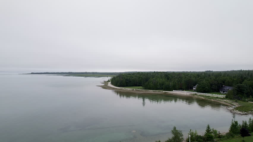 A scenic aerial drone video clip flying along the vibrant shoreline of Mackinaw City, Michigan, where the waters of Lake Michigan and Lake Huron meet at the historic Straits of Mackinac.