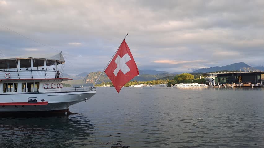 Traditional paddle steamer boat on Lake Lucerne with Swiss flag waving against mountains