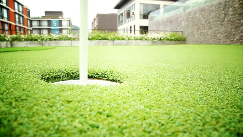 Close-up of putting green nestled in urban setting surrounded by modern architecture, highlighting leisure and sport. Setting invites relaxation and fun for all ages.