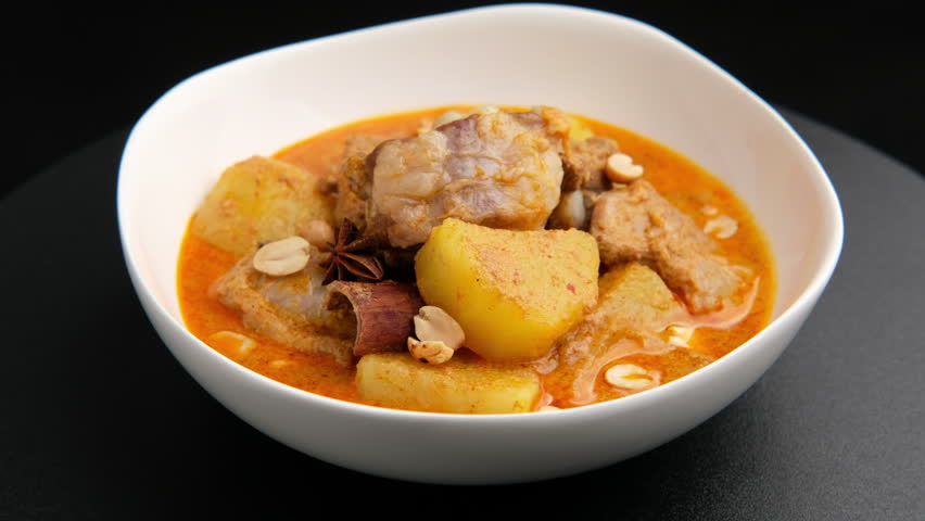 Massaman Curry with baby pork ribs (pork cartilage).Cooked pork meat and potatoes groundnut with massaman curry paste in coconut milk on white bowl.asian food.