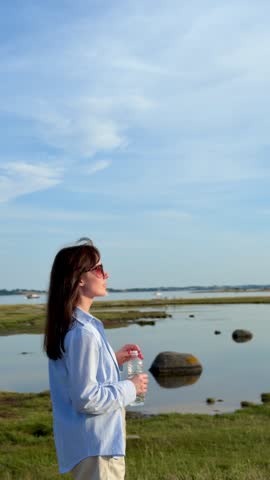Woman drinking water by the lake