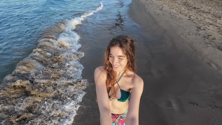 Young woman enjoying a peaceful summer vacation by the ocean, experiencing a relaxing beach moment surrounded by nature. Authentic travel lifestyle content representing happiness, freedom, wellness, relaxation and emotional connection with the sea.