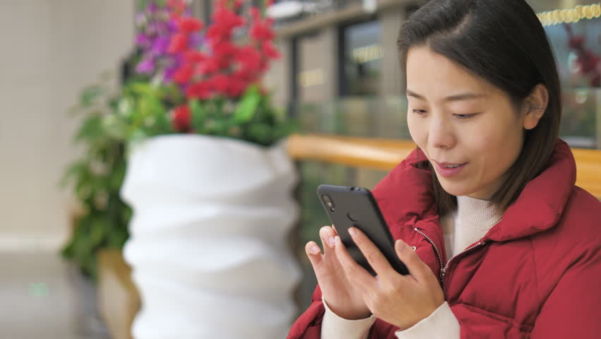 Asian women from East Asia, including China, use their mobile phones to communicate in a shopping mall.
