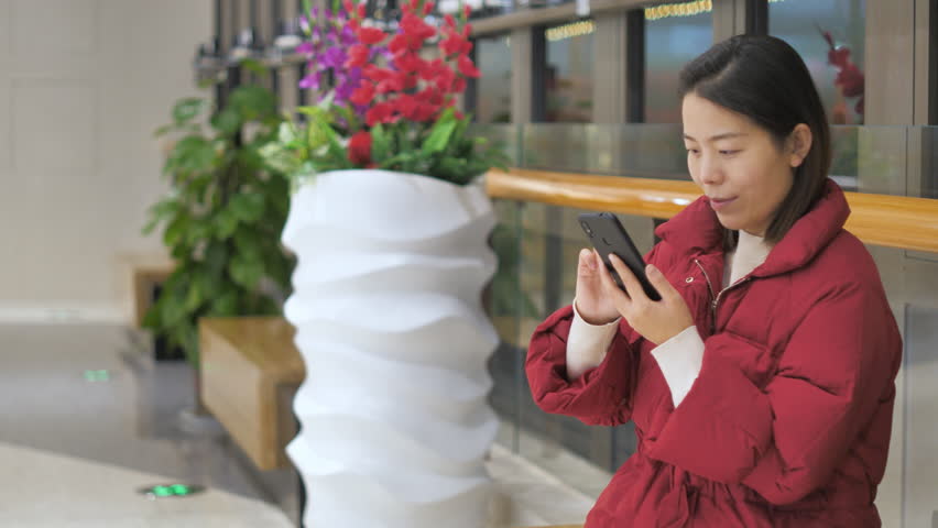 Asian women from East Asia, including China, use their mobile phones to communicate in a shopping mall.