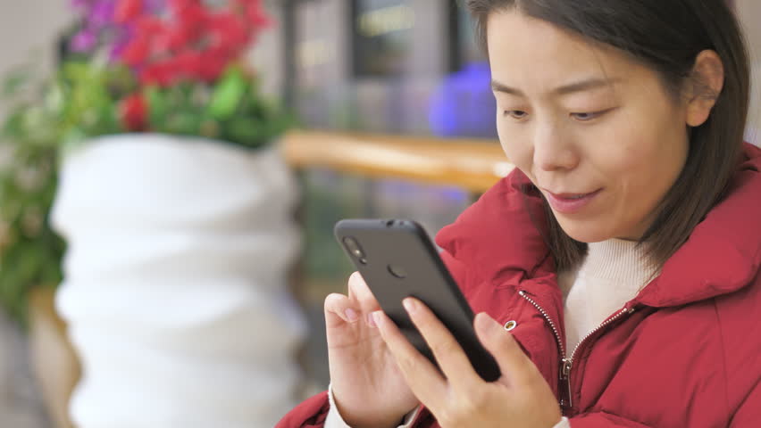 Asian women from East Asia, including China, use their mobile phones to communicate in a shopping mall.