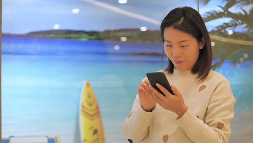 Asian women from East Asia, including China, use their mobile phones to communicate in a shopping mall.