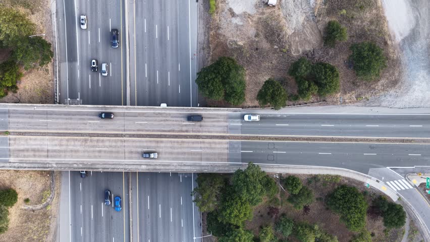 Aerial top down view of a highway overpass and multi lane freeway intersection with driving cars