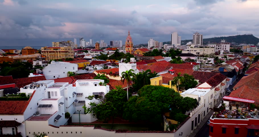 Aerial dolly to Cartagena historic center with cathedral of Santa Catalina de Alejandria and colonial rooftops, drone establishing backdrop