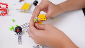 Close up of child hands assembling 3D printed robot model on table. Concept of STEM education, robotics learning, creativity, and technology development - Powered by Shutterstock - Get 15% off with code: PIKWIZARD15