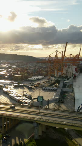 High angle shot of a busy maritime cargo port in Gdynia, Poland, featuring gantry cranes and shipping containers during golden hour. Useful for logistics, global trade, and supply chain concepts.