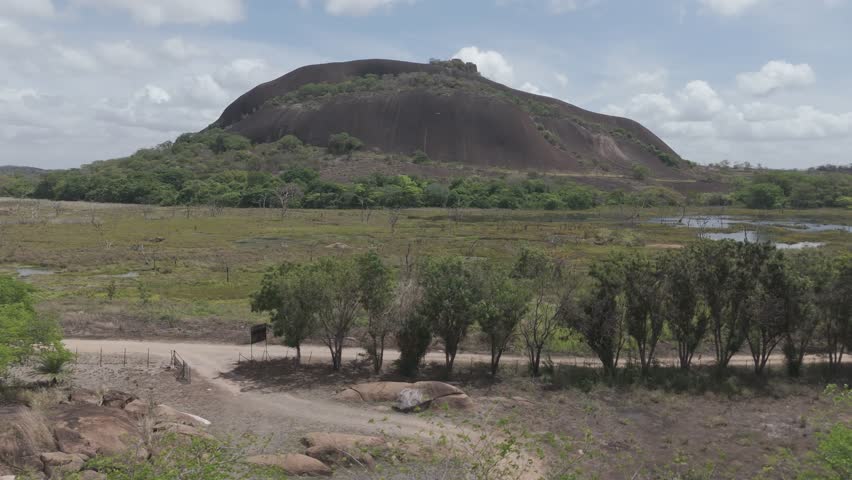 Cinematic panoramic aerial shot revealing a majestic natural mountain dome next to a swamp.