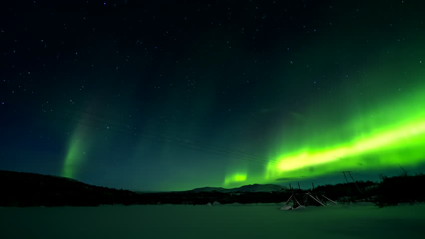 Aurora borealis stretches across the night sky over snowy Finland beneath bright stars, dancing until cloud cover hides the sky