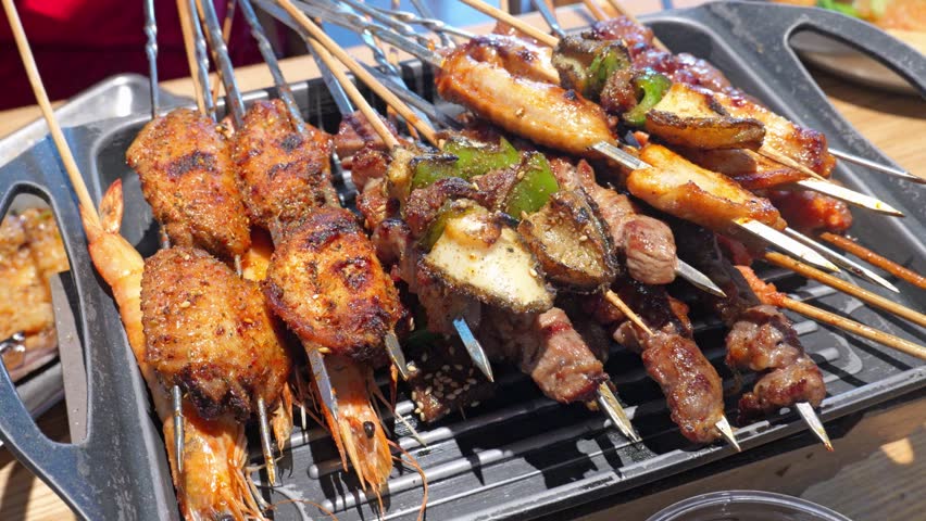 Assorted Chinese barbecue chuanr meat and seafood skewers on table grill