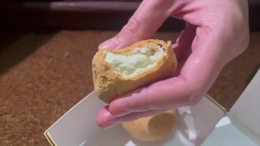 Hand holding creamy durian filled cream puff