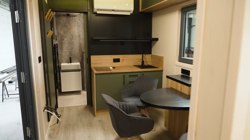 Modern interior of a small, prefabricated mobile home with a kitchen and dining area