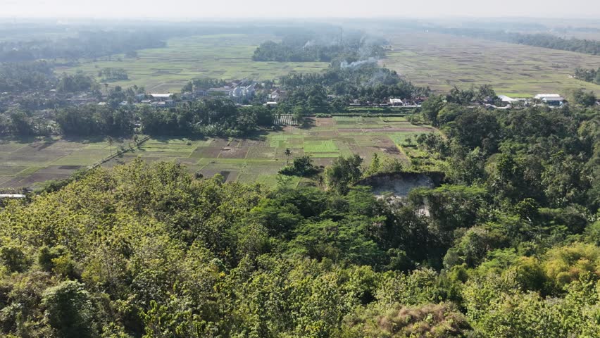 Aerial video shows farmland fields trees and a small village from above highlighting rural life and expansive landscapes