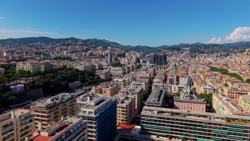 Wide aerial shot of Genoa city center with dense buildings and distant green hills
