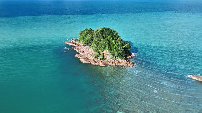Experience an immersive aerial journey above Punggur Island, Bangka, an unspoiled tropical destination surrounded by crystal-clear turquoise waters and striking granite rock formations. This cinematic drone footage captures the island from an elevated perspective, revealing its lush green forest canopy, rugged rocky shoreline, and calm coastal environment embraced by the vast ocean. The vibrant contrast between emerald vegetation, warm granite textures, and brilliant blue sea creates a breathtaking natural composition ideal for travel, tourism, environmental, and destination-related projects. Gentle waves move gracefully around the island while the expansive horizon enhances the feeling of freedom, tranquility, and exploration. The isolated setting highlights the untouched beauty of this hidden paradise, making it a compelling visual asset for documentaries, promotional campaigns, social media productions, television programs, and commercial advertising. Rich tropical scenery combined with pristine coastal landscapes offers an authentic representation of Indonesia