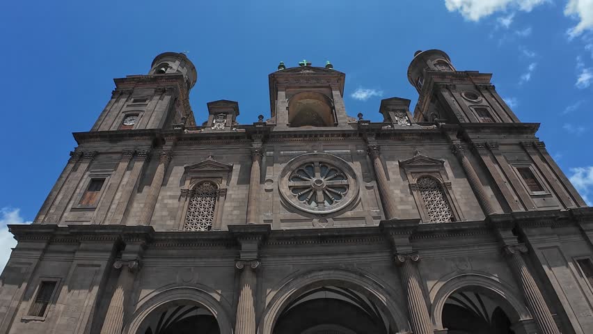 A stone facade of the grand Las Palmas Cathedral in Las Palmas, Gran Canaria, Spain, under a bright blue sky