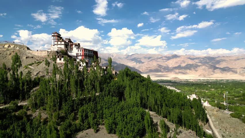 Aerial view of Matho Gompa monastery surrounded by lush trees and rugged Himalayan mountains in Matho, Ladakh, India.