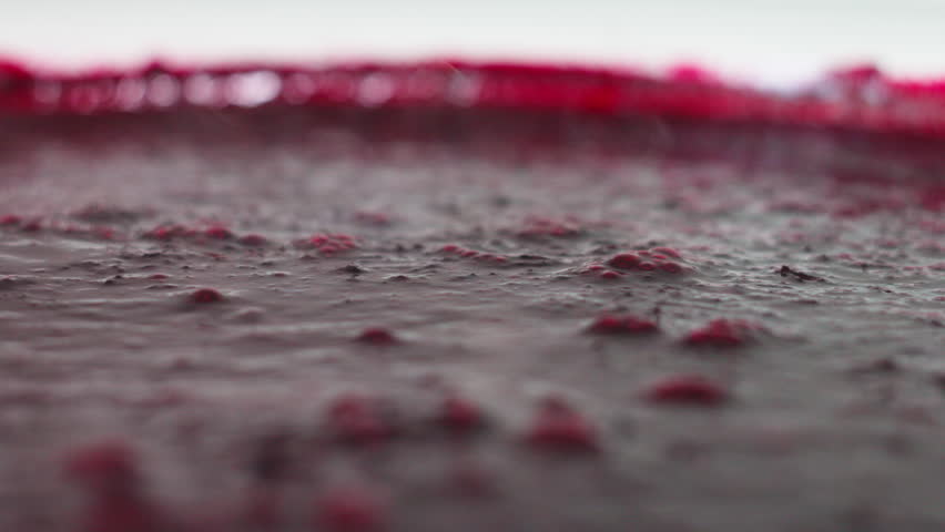 A detailed close-up shot capturing the thick and velvety texture of a dark purple fruit smoothie. Small air bubbles rise to the surface, creating a dynamic visual of fresh, healthy, and blended
