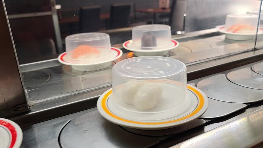 Sushi plates glide along a conveyor belt inside a Japanese restaurant, colorful dishes passing diners, kaiten sushi dining, casual eatery experience.
