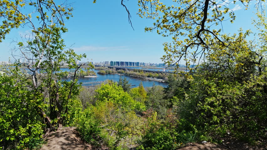 High angle panoramic view of Kyiv city skyline and Dnieper river in Ukraine seen through lush green trees on a bright sunny spring day with no people