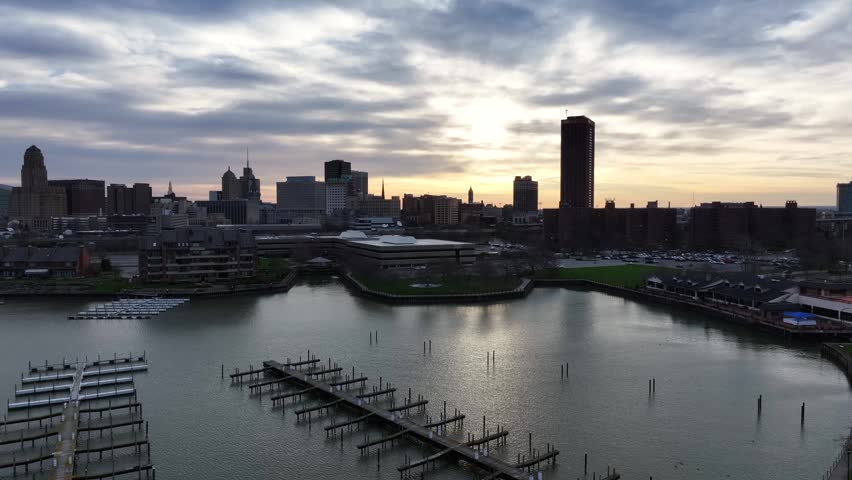 Aerial view of the Buffalo skyline with a marina and calm waterfront under a cloudy sunrise sky in Buffalo, New York, United States.