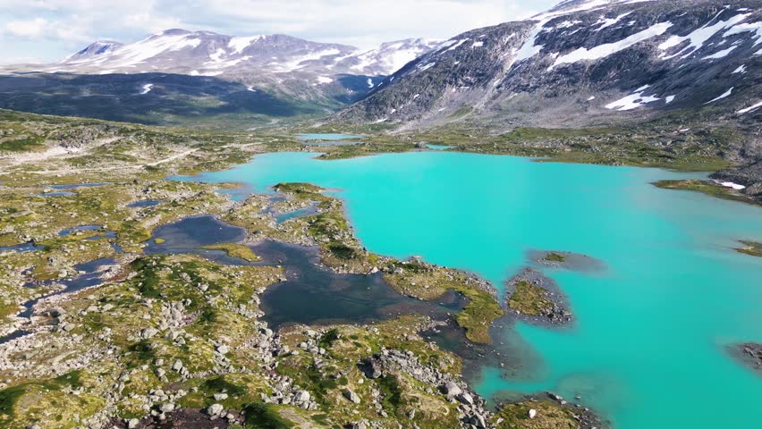Aerial view of the turquoise glacial lakes along the Old Strynefjell Mountain Road, surrounded by rugged snow-capped peaks and rocky terrain in Stryn Municipality, Vestland, Norway.