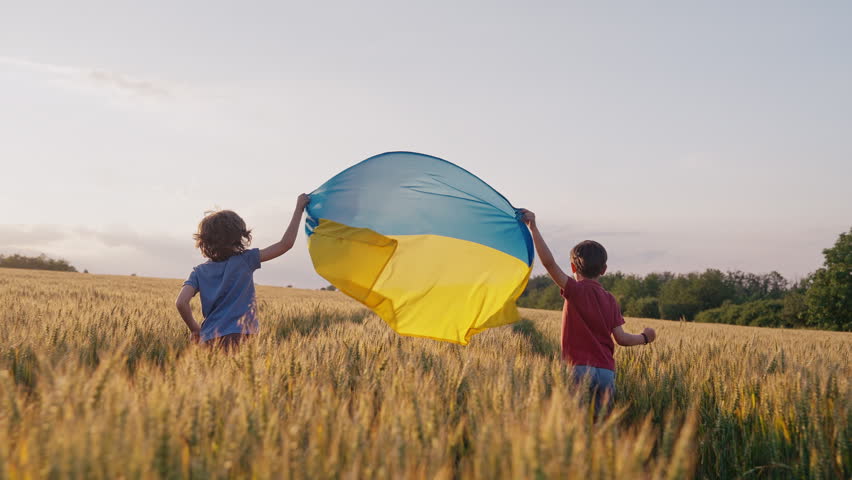Happy little boys - Ukrainian patriots children running with national flag in field, open area. Ukraine, peace, independence, freedom, victory in war.