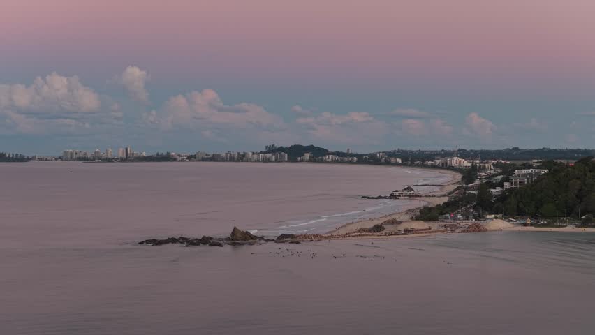 Aerial view of Currumbin Alley with its sandy beach and rocky shoreline under a soft twilight sky in City of Gold Coast, Queensland, Australia.
