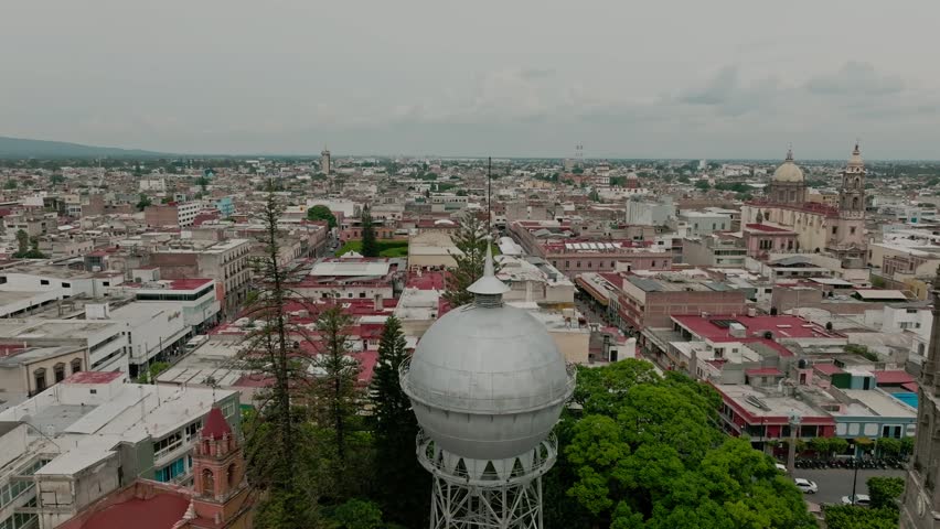 Aerial Drone view of historic city center featuring prominent water tower, church bell tower, and dense urban architecture stretching across expansive cityscape.