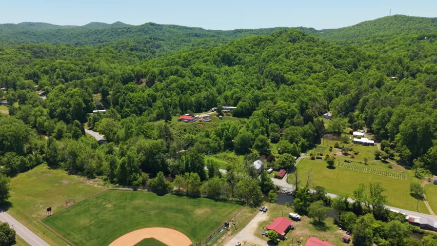 Aerial view of Rosman, North Carolina, showcasing a baseball field surrounded by lush greenery and residential homes in a rural setting