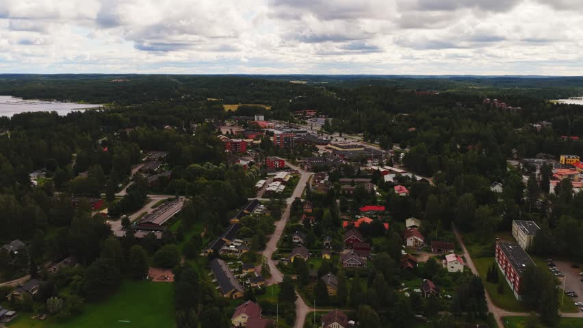 Aerial view of the town of Vaaksy with lush forests, residential houses, and roads under a cloudy sky in Vaaksy, Paijat-Hame, Finland.