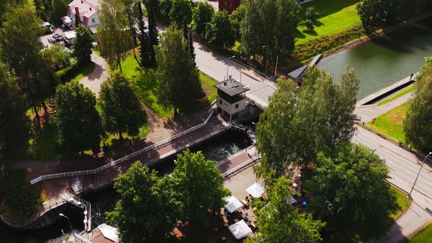 Aerial view of the historic Vaaksy Canal lock and bridge surrounded by lush green trees and summer foliage in Vaaksy, Paijat-Hame, Finland.