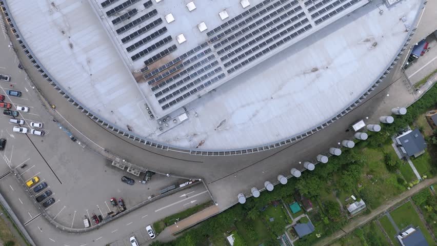Aerial view of large building with solar panels on the roof and adjacent parking lot in Gdansk, Pomeranian Voivodeship, Poland.